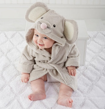 Baby wearing an elephant-themed hooded robe on a white bed.