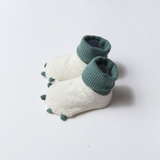 Pair of green and white baby booties on a light gray background