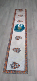Decorative table runner with floral and leaf patterns on a dark surface