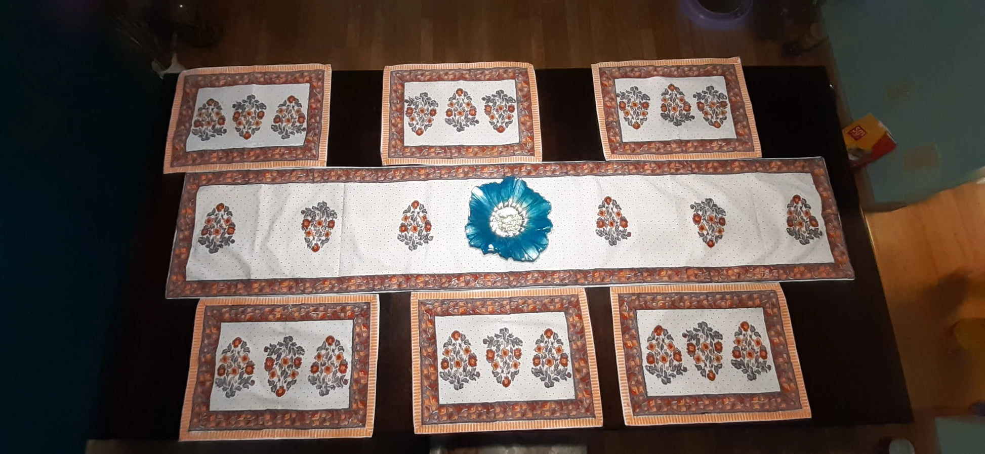 Set of decorative placemats with a central blue emblem on a dark surface