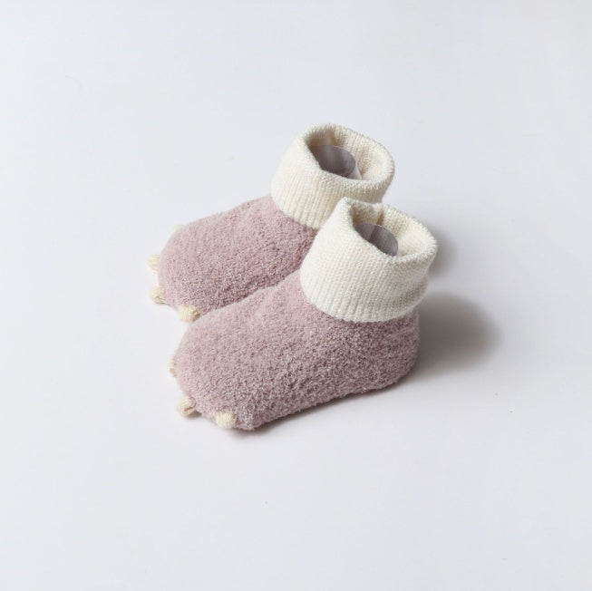 Pair of pink and white baby booties on a light gray background