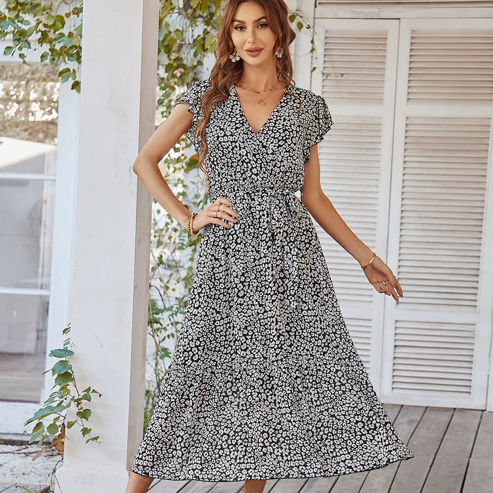 Woman wearing a black and white floral dress standing outdoors.