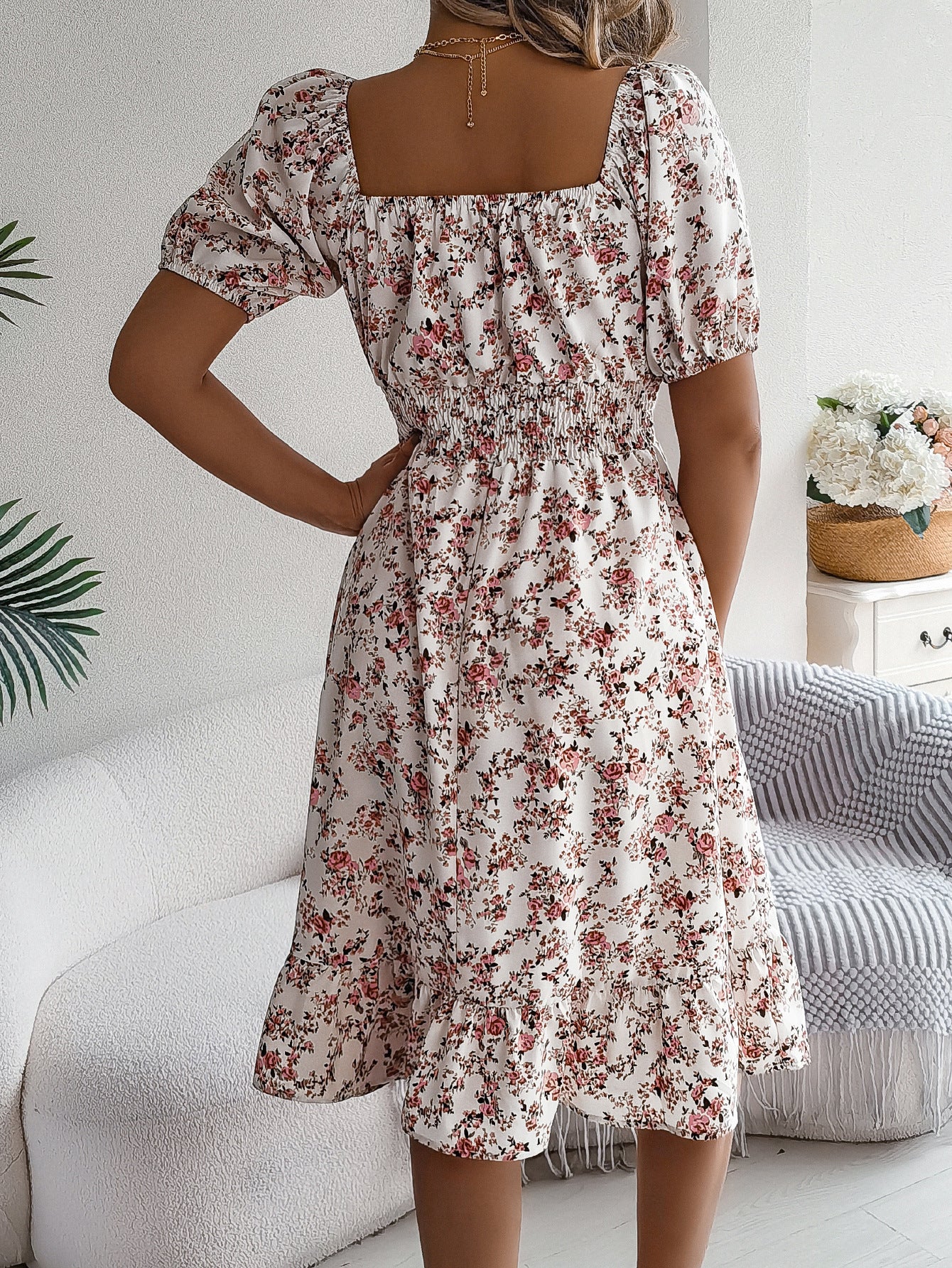 Woman wearing a floral dress in a living room setting