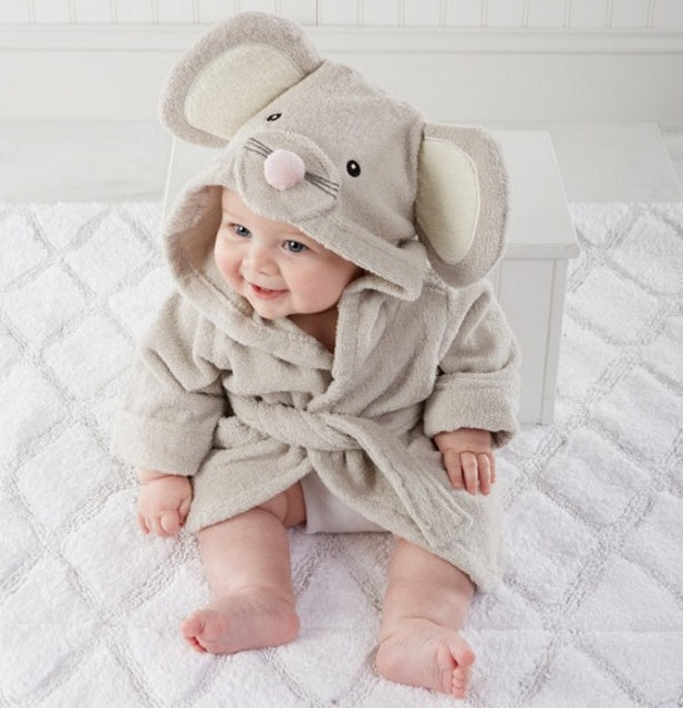 Baby wearing an elephant-themed hooded robe on a white bed.