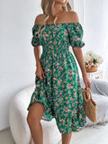 Woman wearing a green floral off-shoulder dress in a bright room.