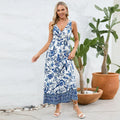 Woman wearing a blue and white floral dress standing outdoors with plants in the background