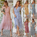 Woman in a pink floral dress standing on a wooden deck.