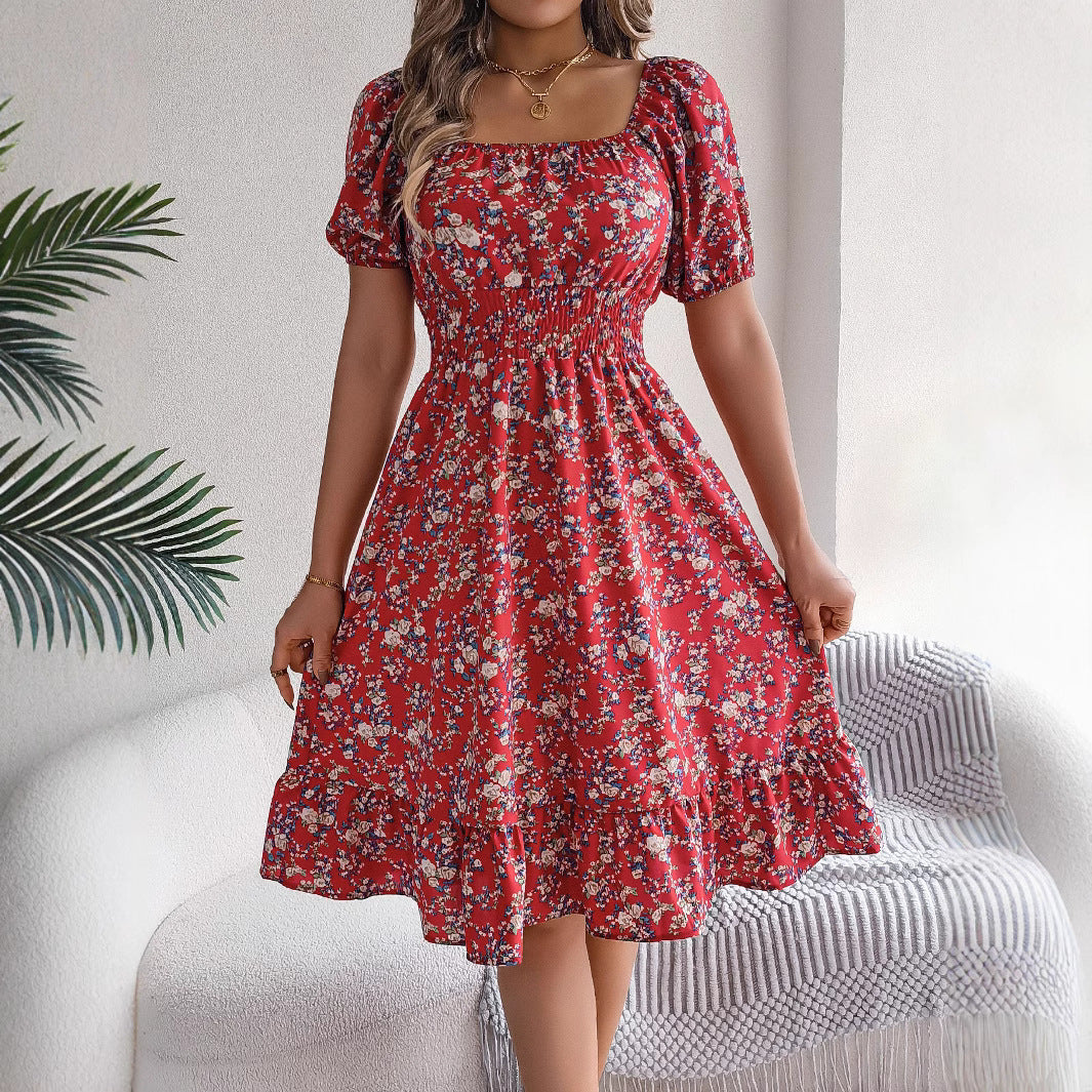 Woman wearing a red floral dress sitting on a white chair with a plant in the background